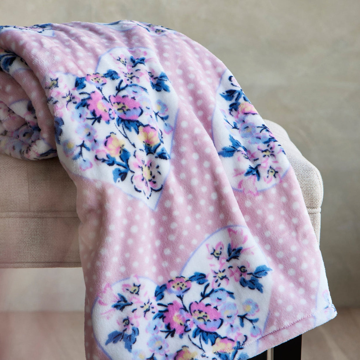 Pink throw blanket with floral pattern draped across chair