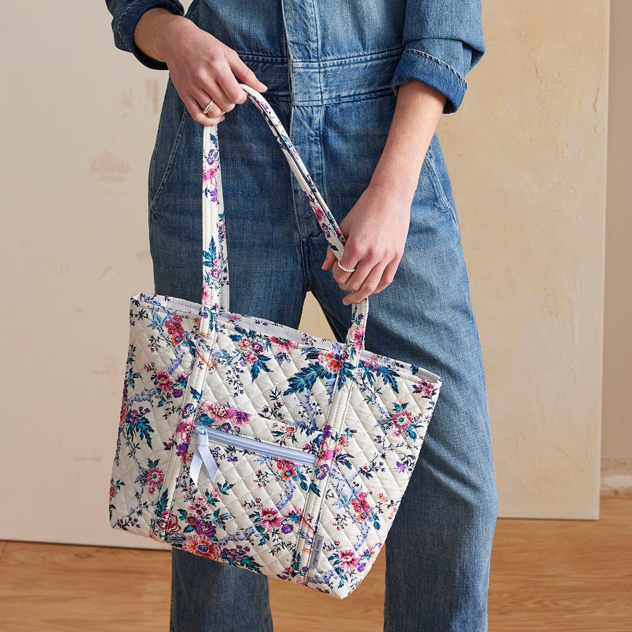 model holding small quilted tote bag with floral pattern