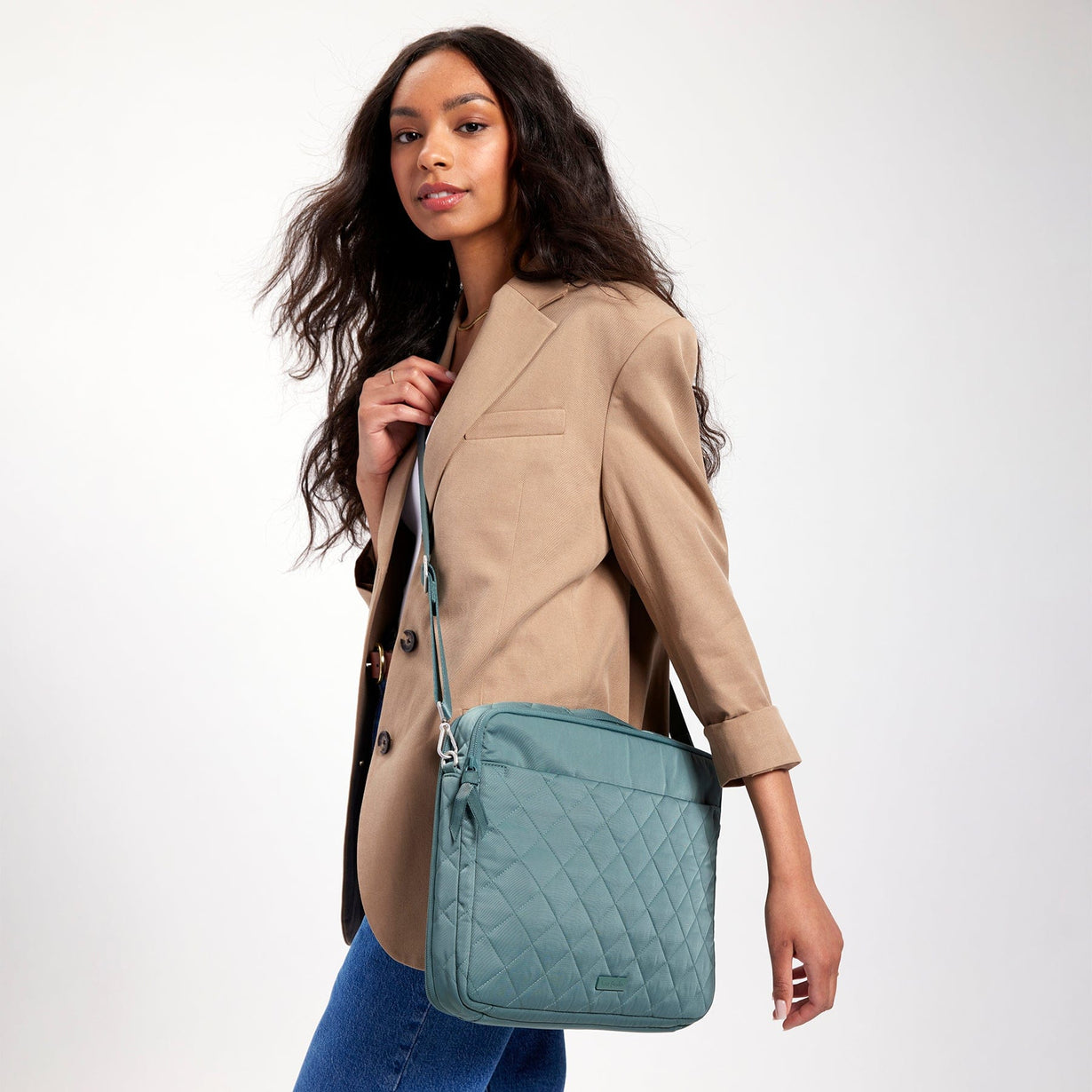 model wearing camel blazer and jeans carrying a lightweight crossbody laptop bag