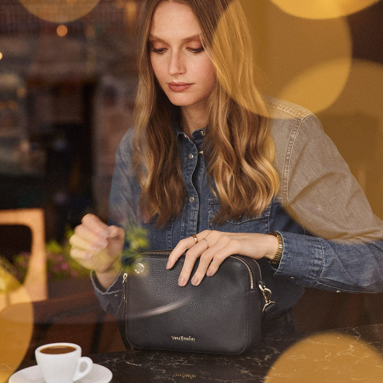 Woman at counter in cafe with black leather handbag