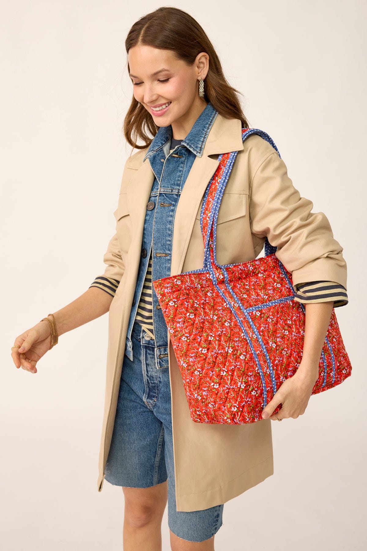 model wearing denim and light brown jacket with large red quilted cotton tote bag slung over shoulder