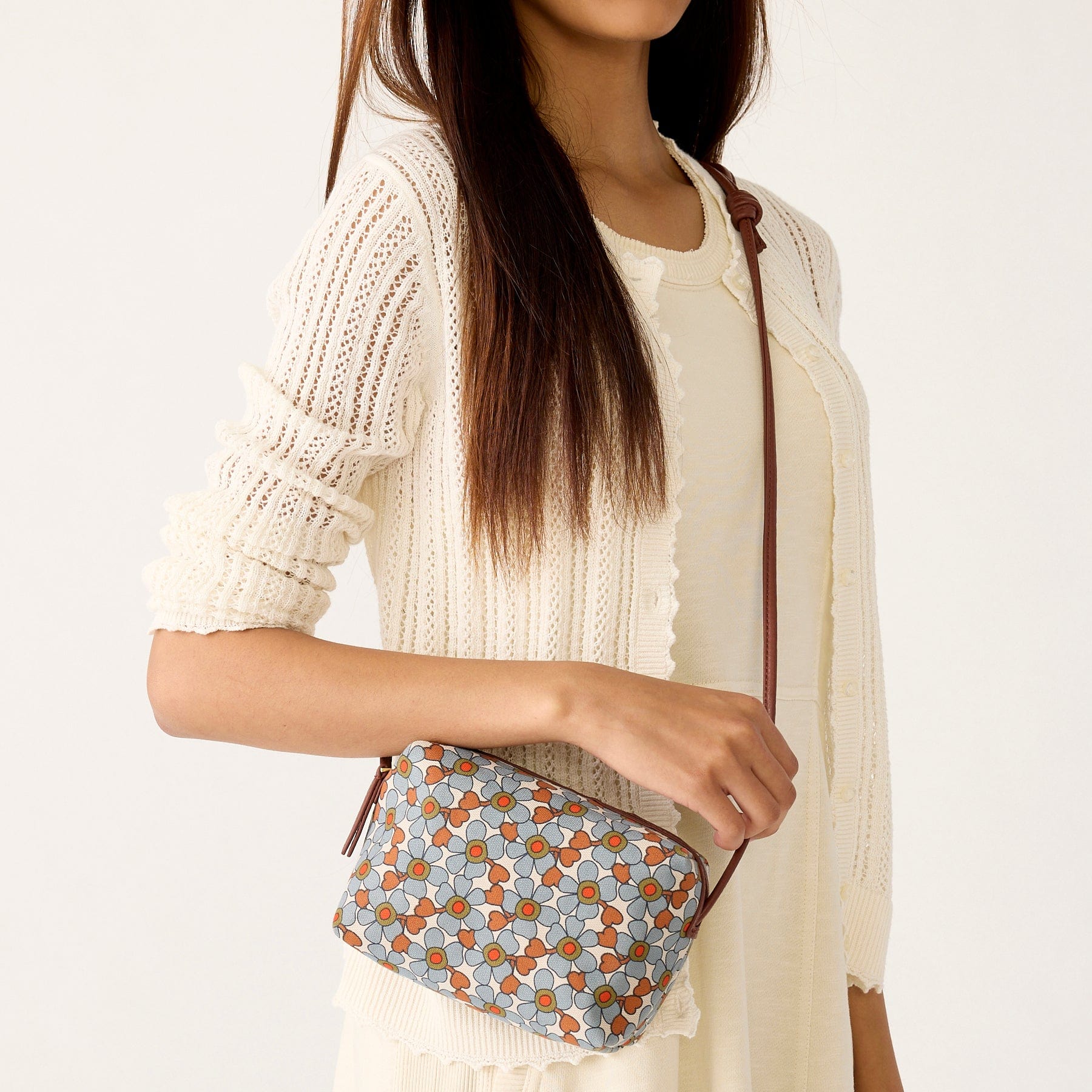 model with cream sweather and crossbody bagk with blue and orange flowers pattern
