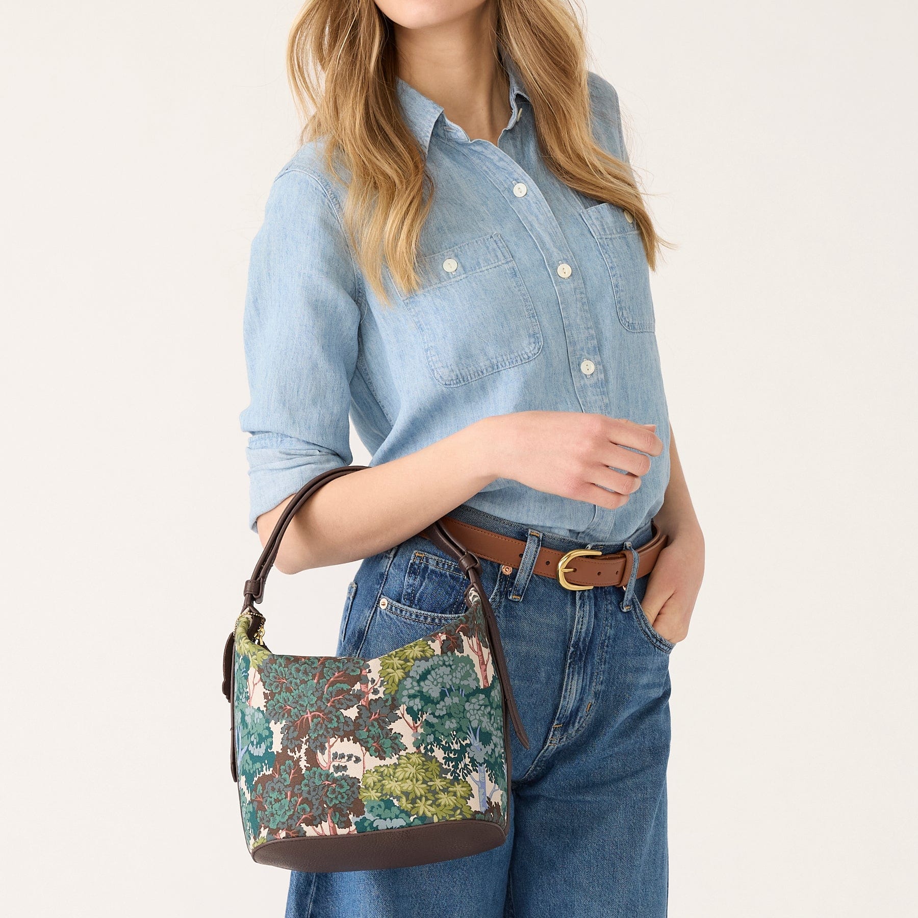 model wearing denim with handbag across arm featuring foliage print