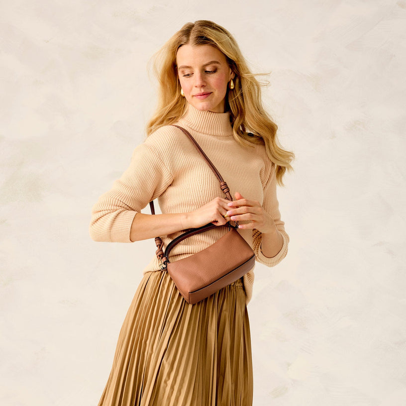 Model holding brown leather crescent style crossbody bag