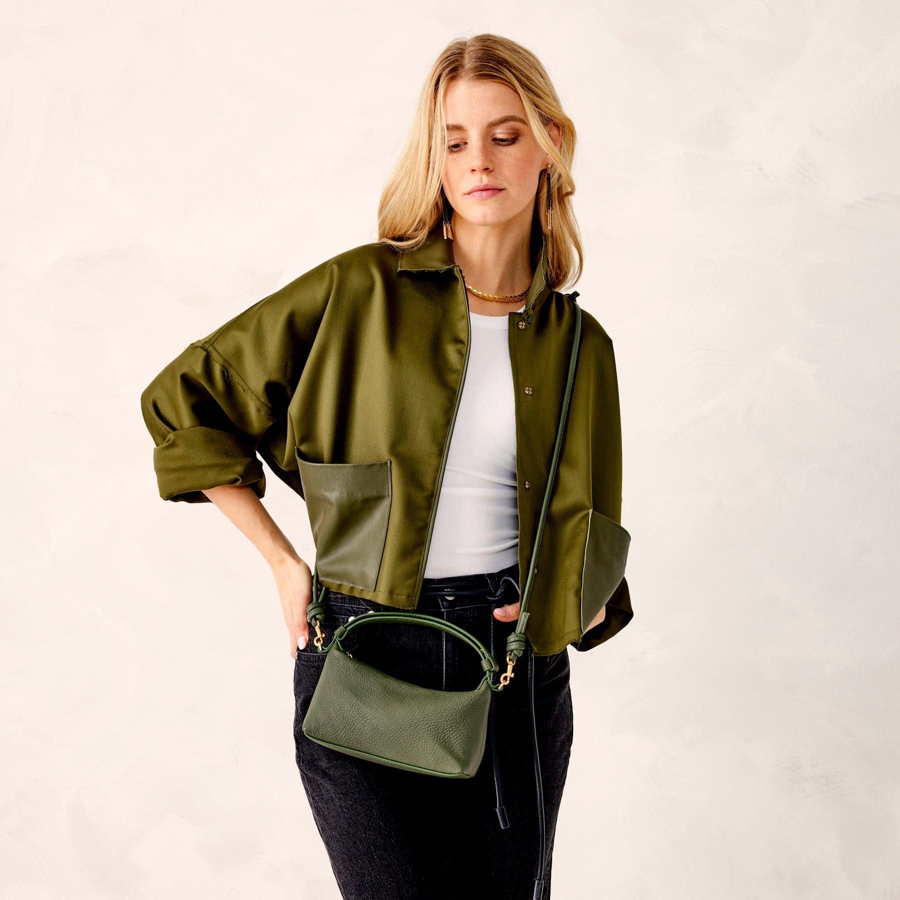 model wearing green silk jacket with dark jeans wearing green leather crossbody bag