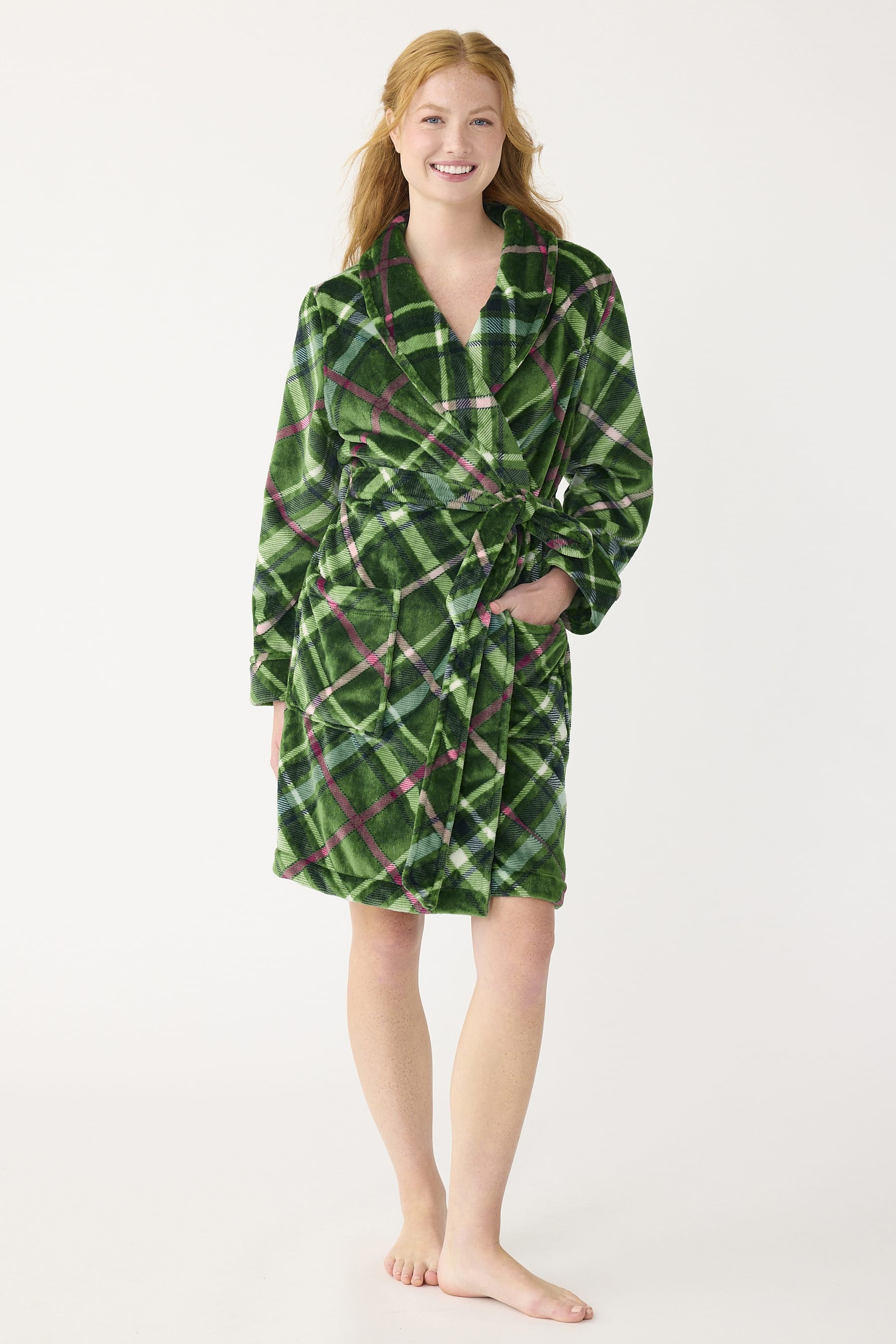 model wearing knee-length dark green plaid fleece robe with hand in front pocket