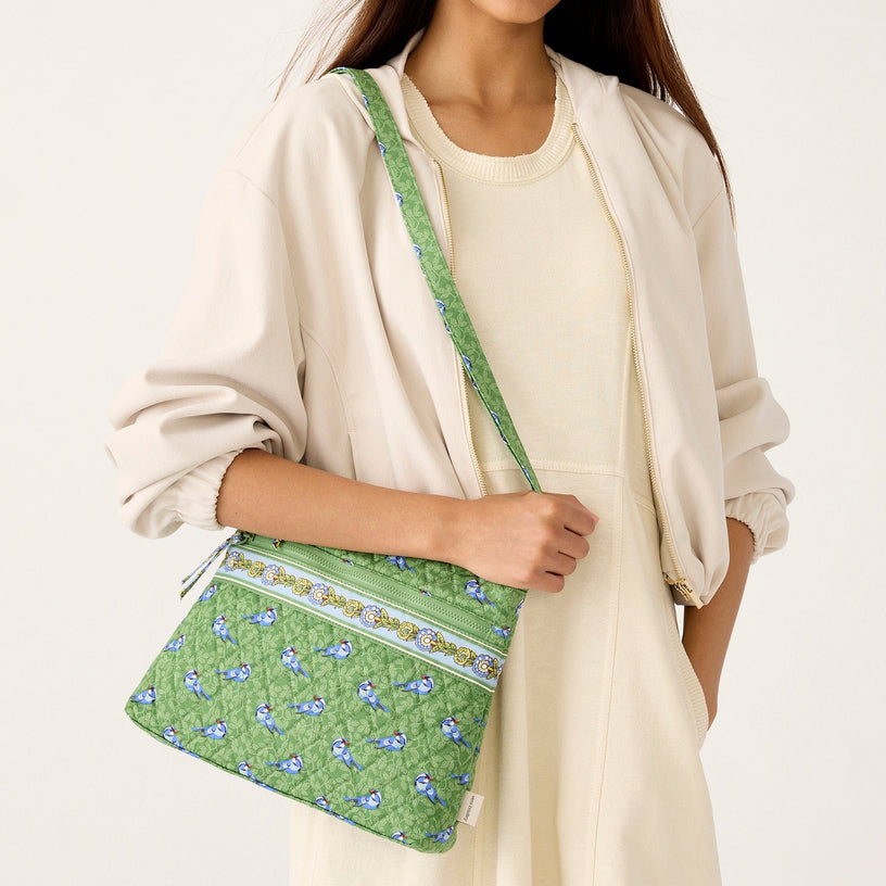 model holding green quilted crossbody bag with blue birds pattern