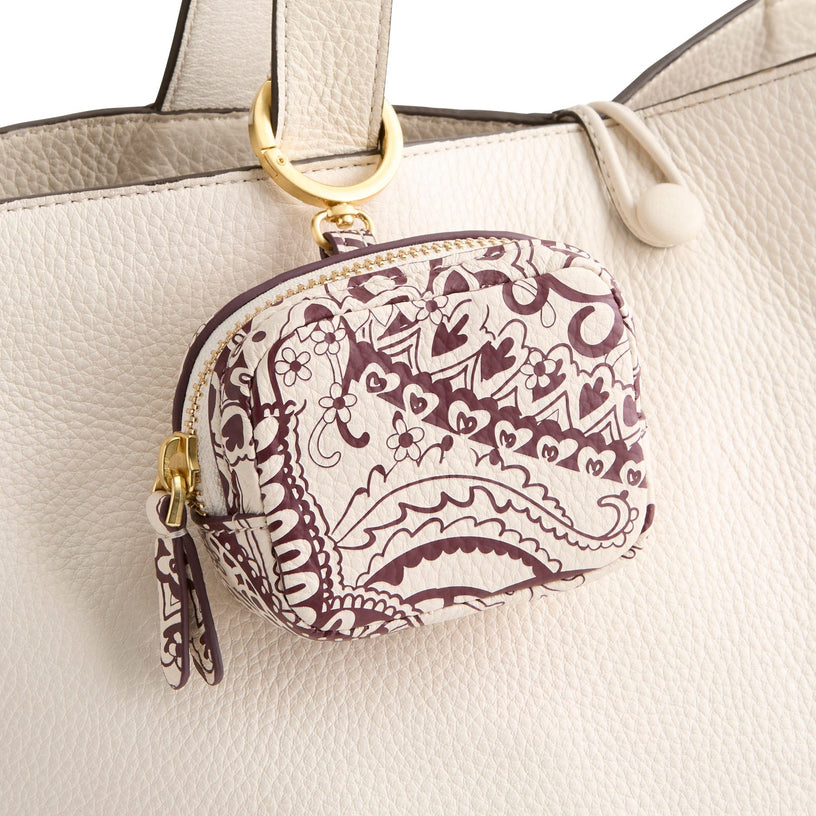 white leather earbud case with red pattern attached to handbag