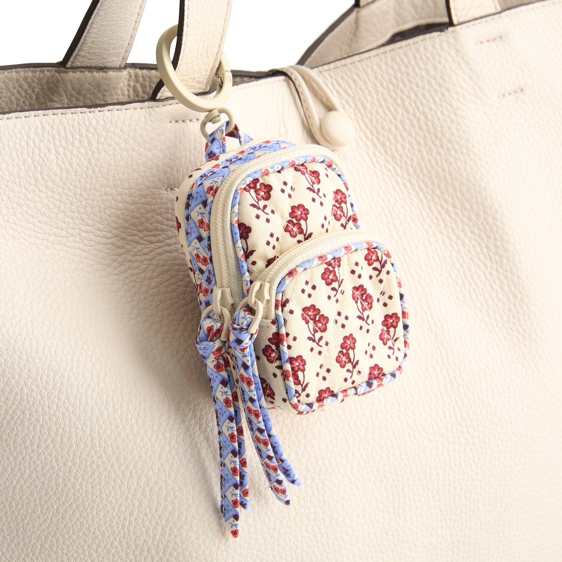 mini backpack bag charm with gold hoop attaching it to cream leather purse strap