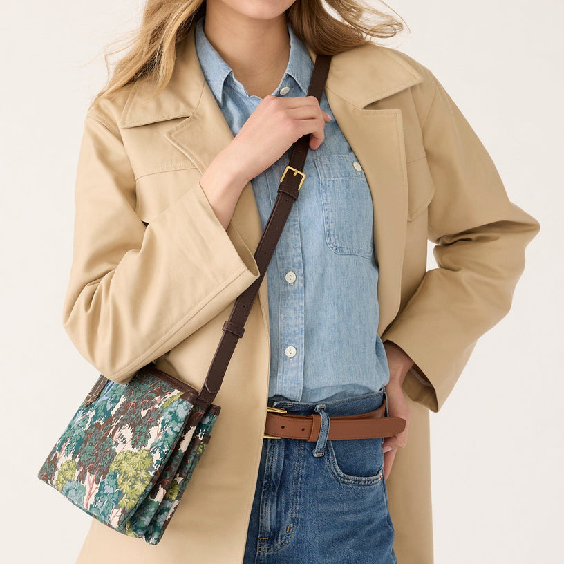 Model wearing beige jacket and crossbody bag with forest pattern and brown adjustable strap