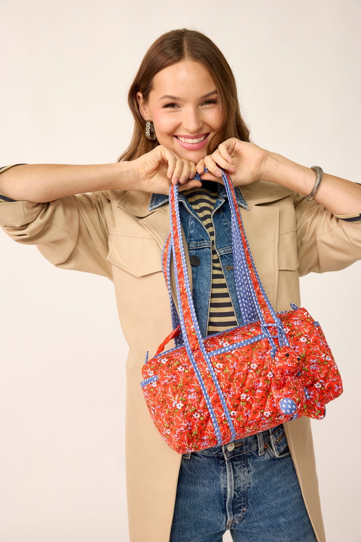 smiling model wearing brown jacket holding vera bradley original 100 red quilted cotton handbag