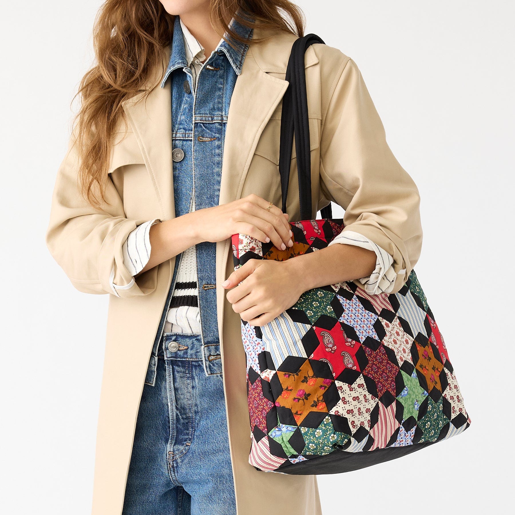 model wearing light brown jacket with multicolor patchwork style tote bag over shoulder