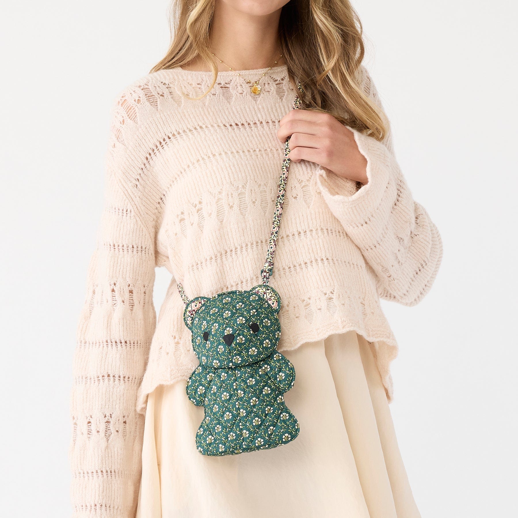 model wearing cream colored outfit with green cotton crossbody bag shaped like a bear