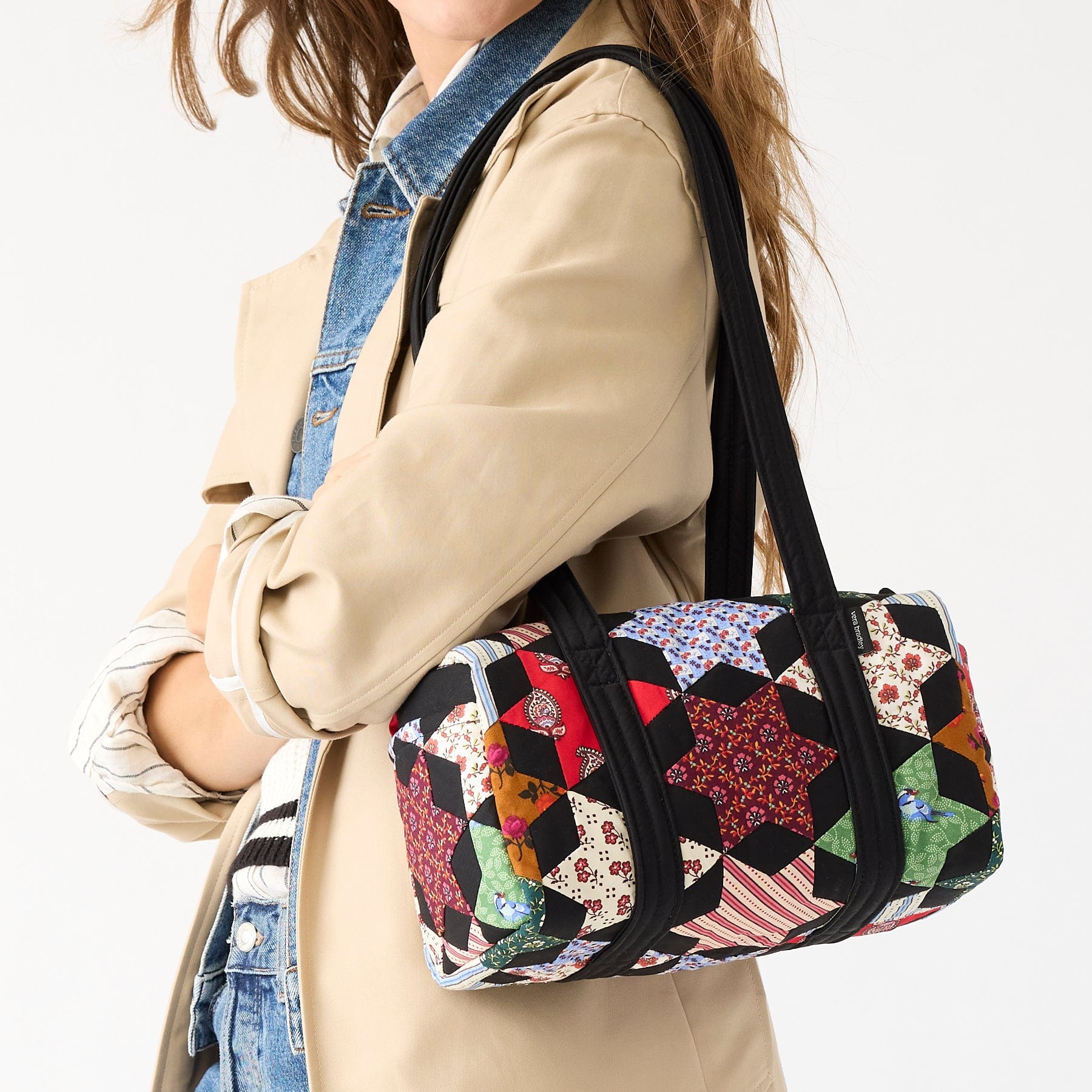 model wearing light brown jacket with cotton vera bradley handbag over shoulder in patchwork pattern
