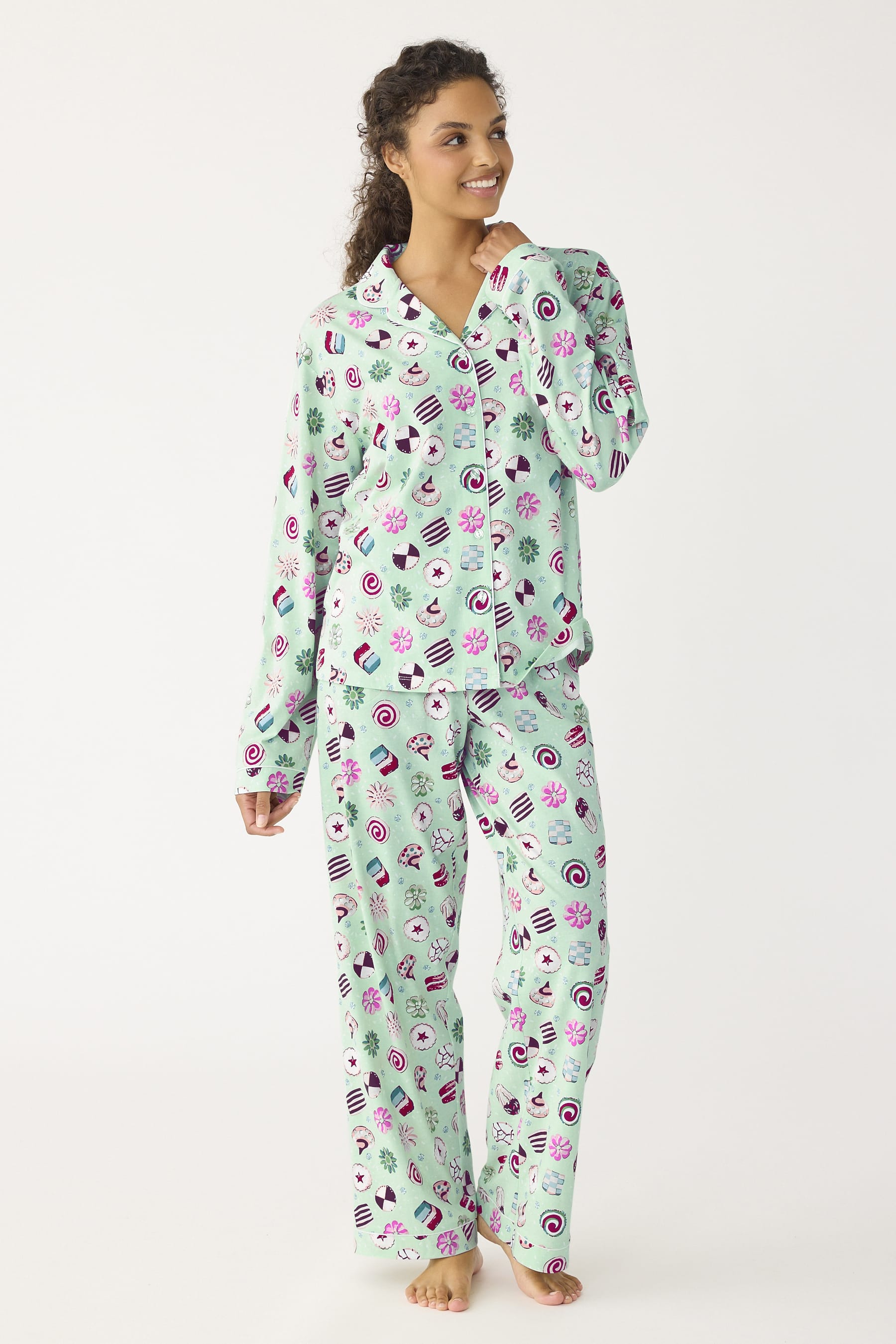 model wearing mint green button down pajamas shirt and matching pants with playful cookies pattern