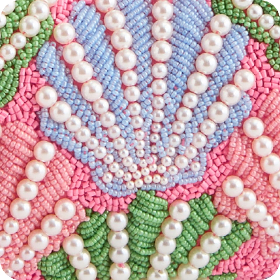 Extreme close-up of hand beadwork: pearls and seed beads in floral pattern