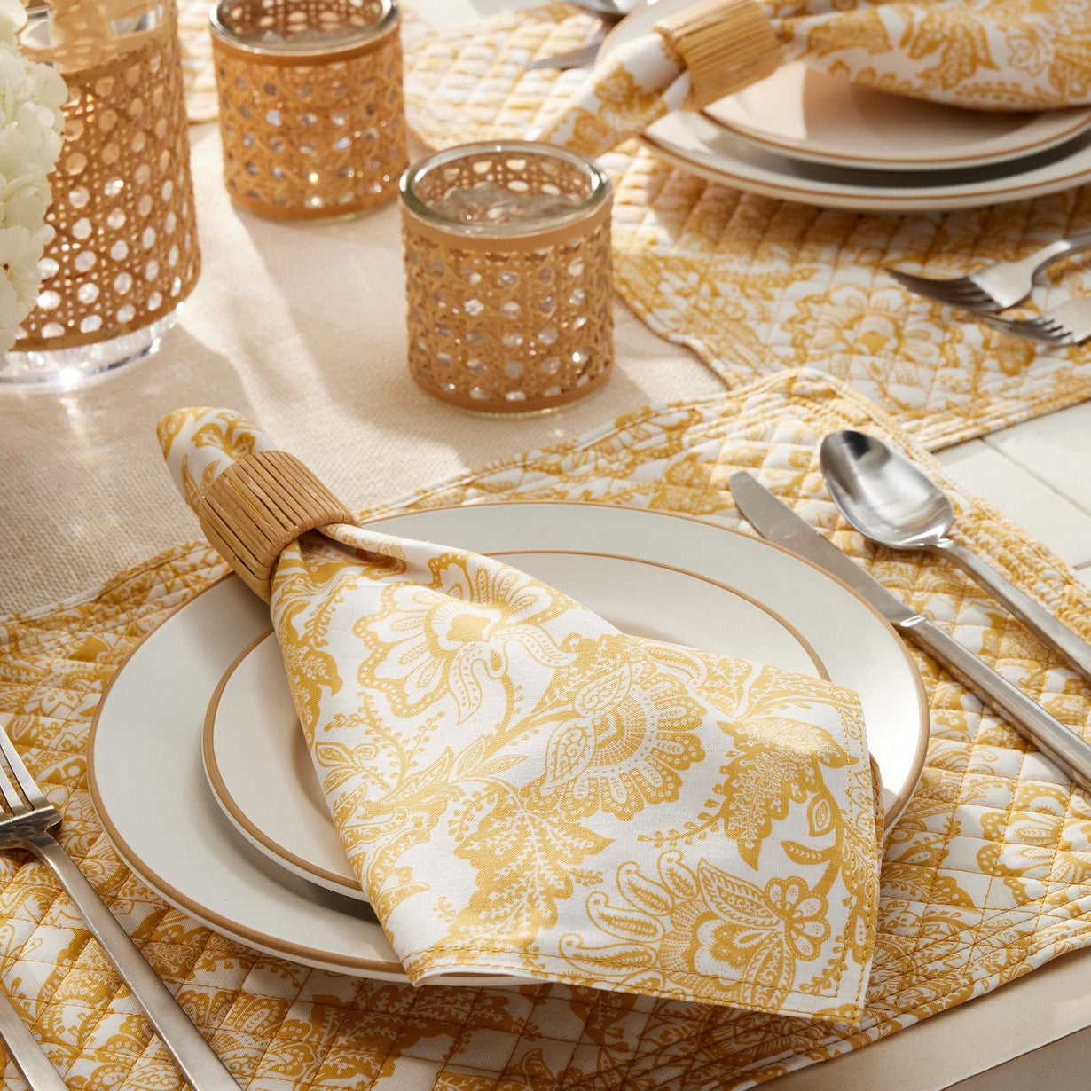 Place-settings with placemats and napkins featuring gold filigree design