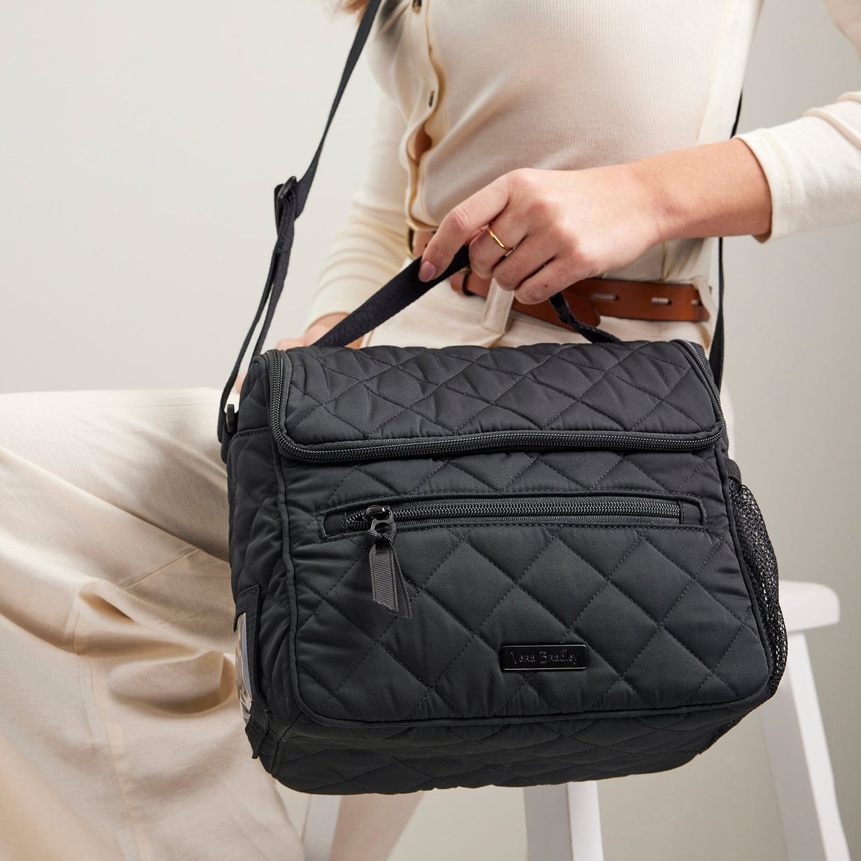 woman holding quilted black crossbody lunch bag